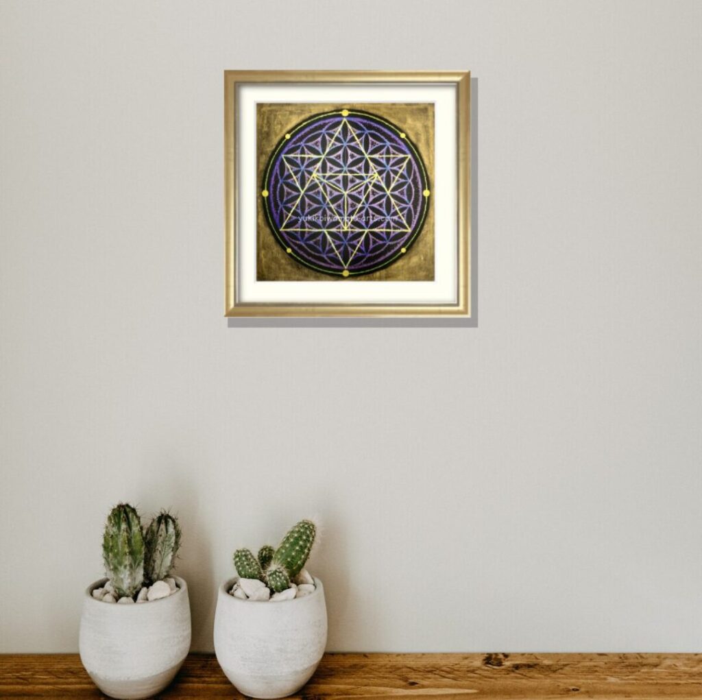 サボテン鉢のあるシェルフに飾られた神聖幾何学アート「宇宙」。シャンパンゴールド額装が自然の生命力と調和し、空間のエネルギーを整える。20cm角の手描き原画。